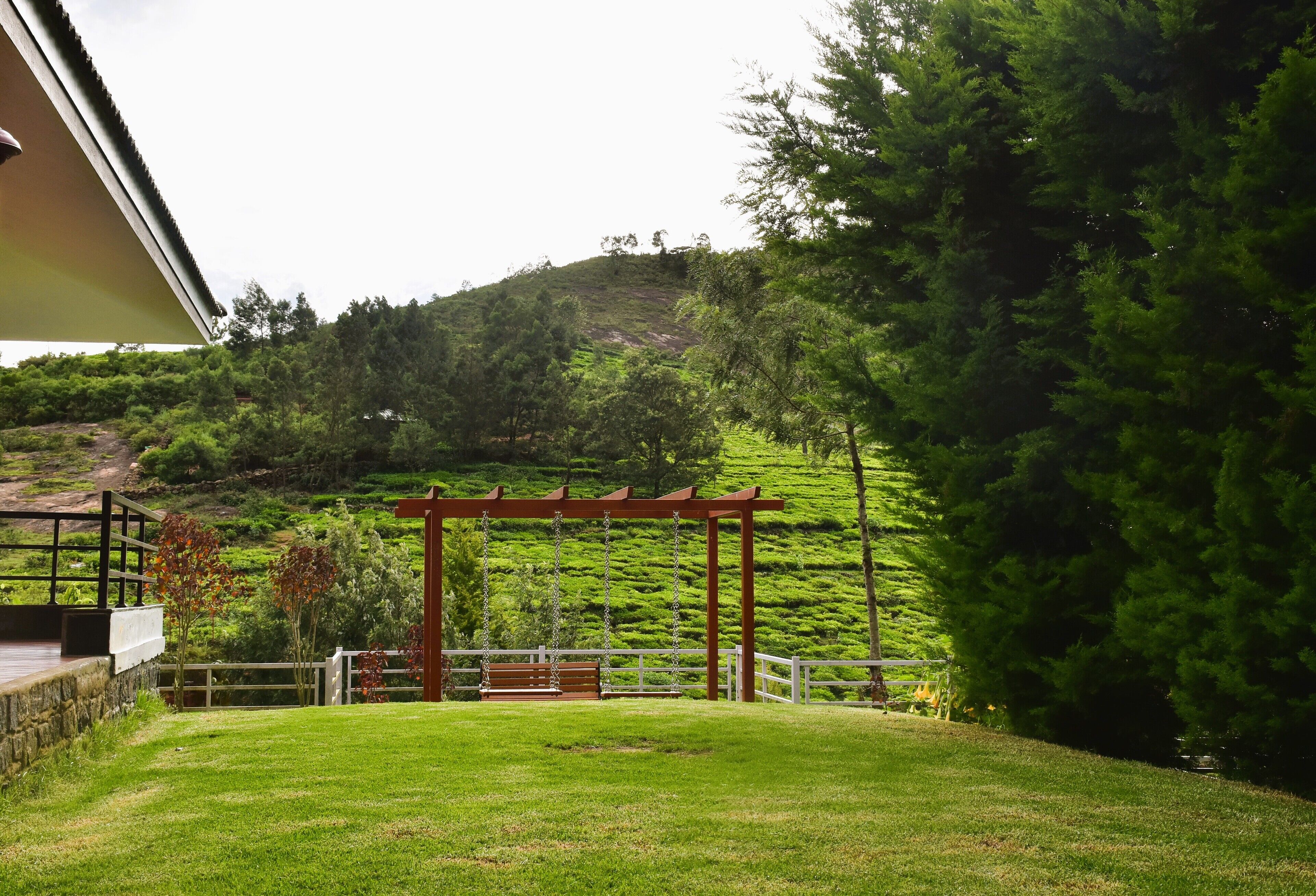 A grassy area with a wooden swing set and a pergola.