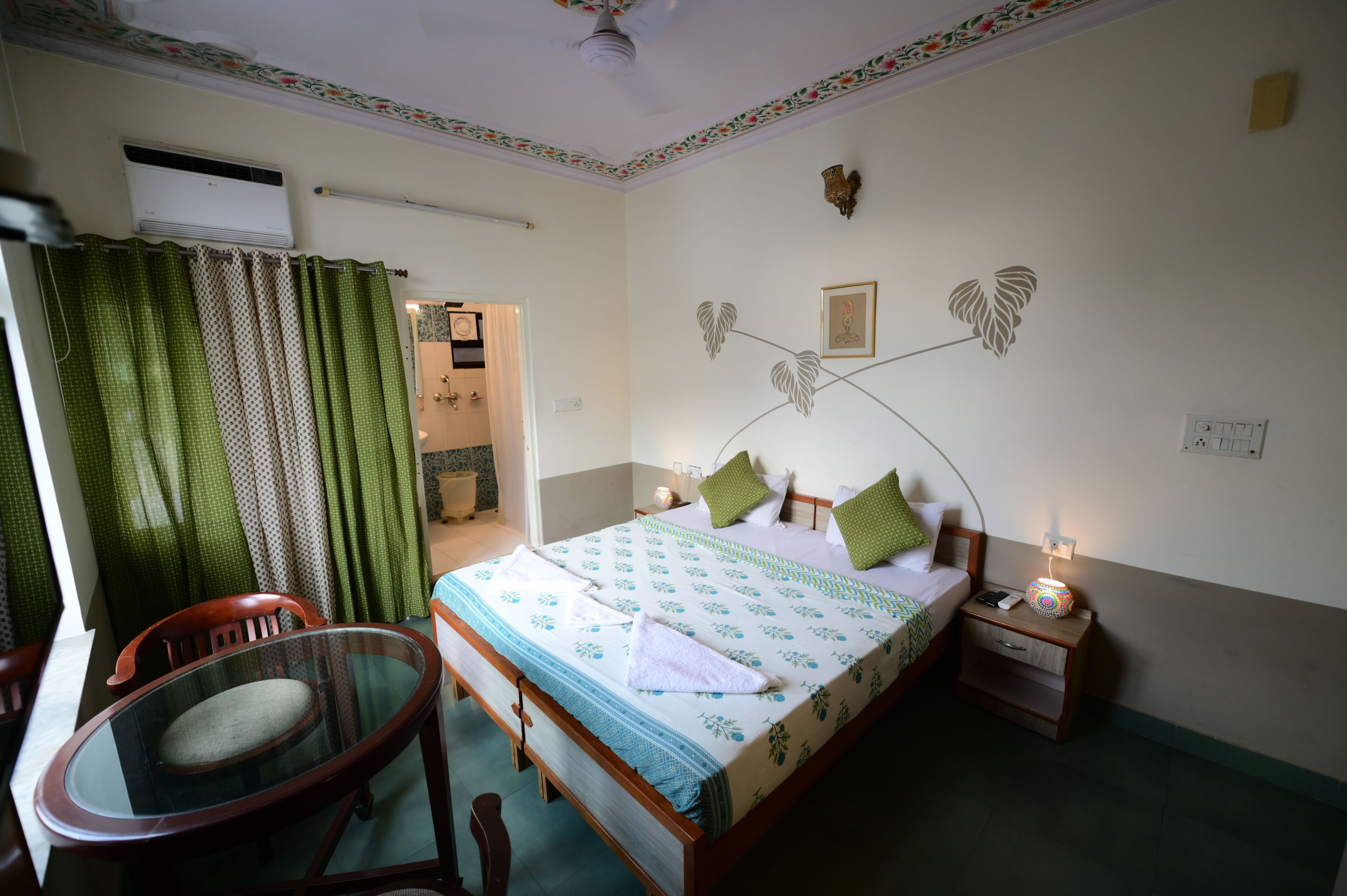 Une chambre à coucher avec un lit, une table de chevet avec une lampe, une chaise et une fenêtre avec des rideaux.