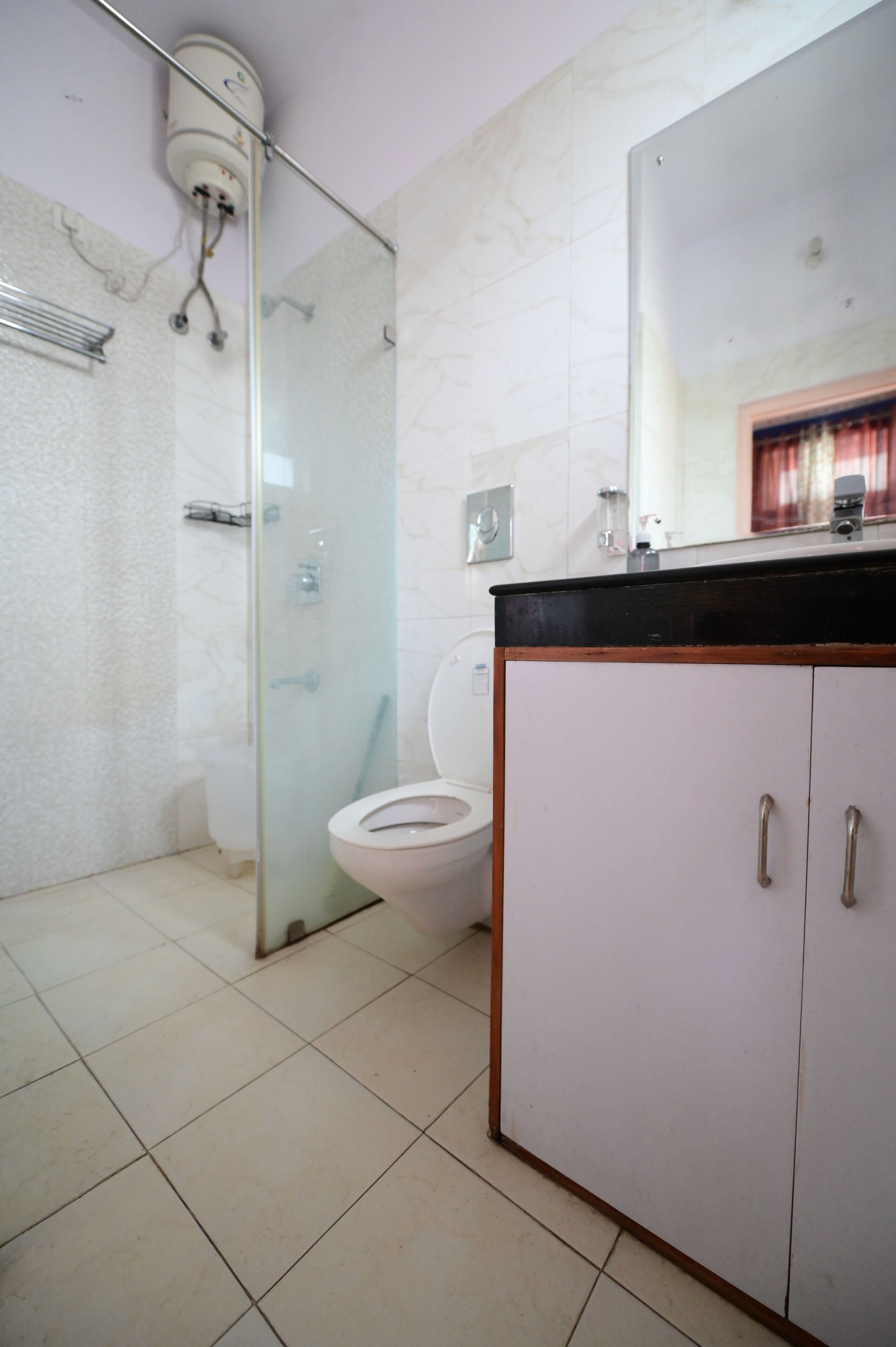 A bathroom with a glass-enclosed shower, a toilet, and a cabinet with two doors.