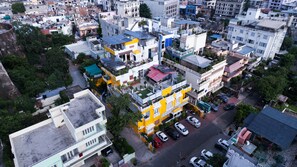 Vue aérienne d’une zone urbaine densément peuplée, avec divers bâtiments, notamment des immeubles à plusieurs étages dotés de balcons et de panneaux solaires.