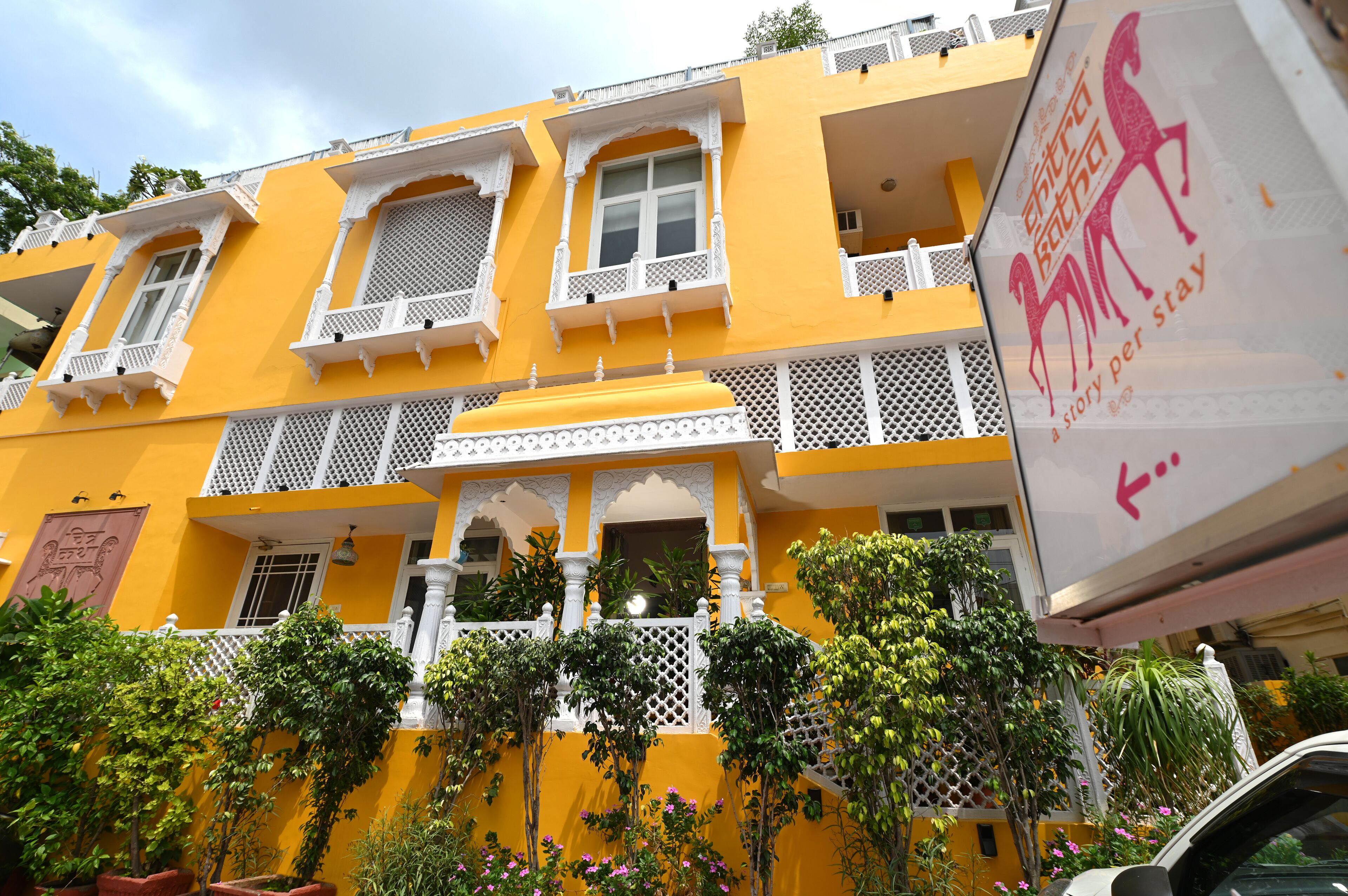 A yellow building with white balconies and lattice railings.