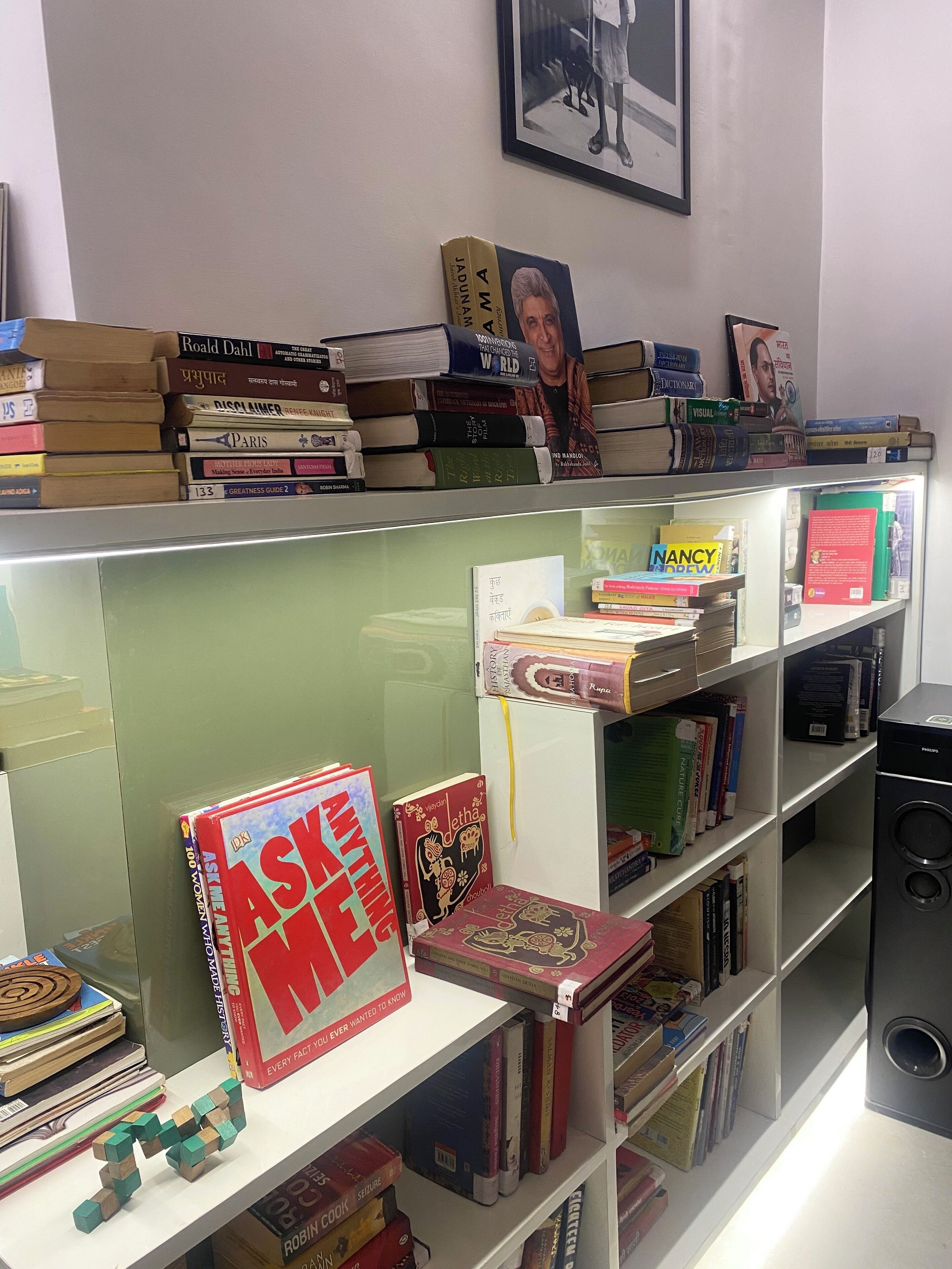 A bookshelf with various books, a framed picture on the wall, and a speaker on the right.