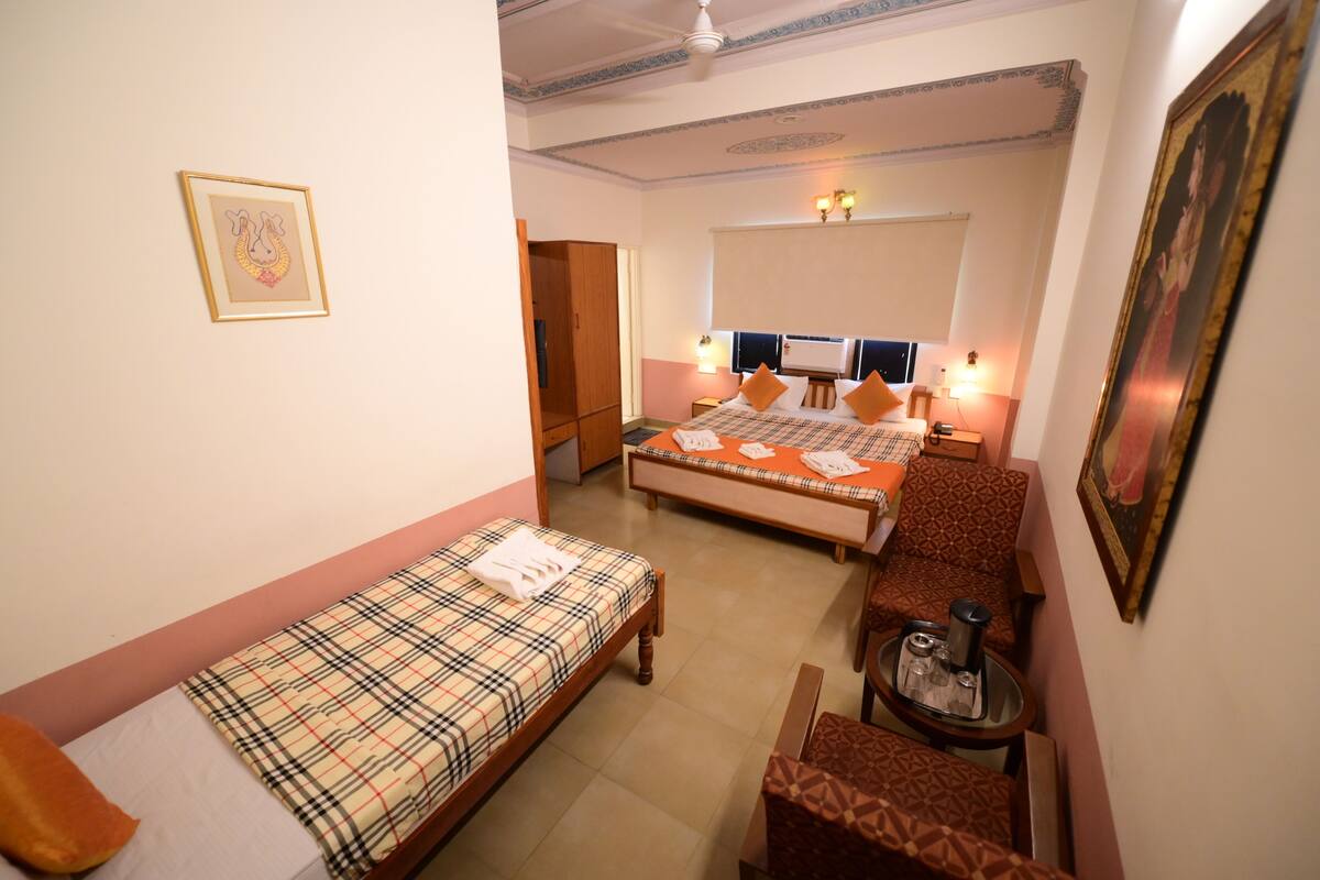 Habitación de hotel con dos camas, una mesita y una silla.
