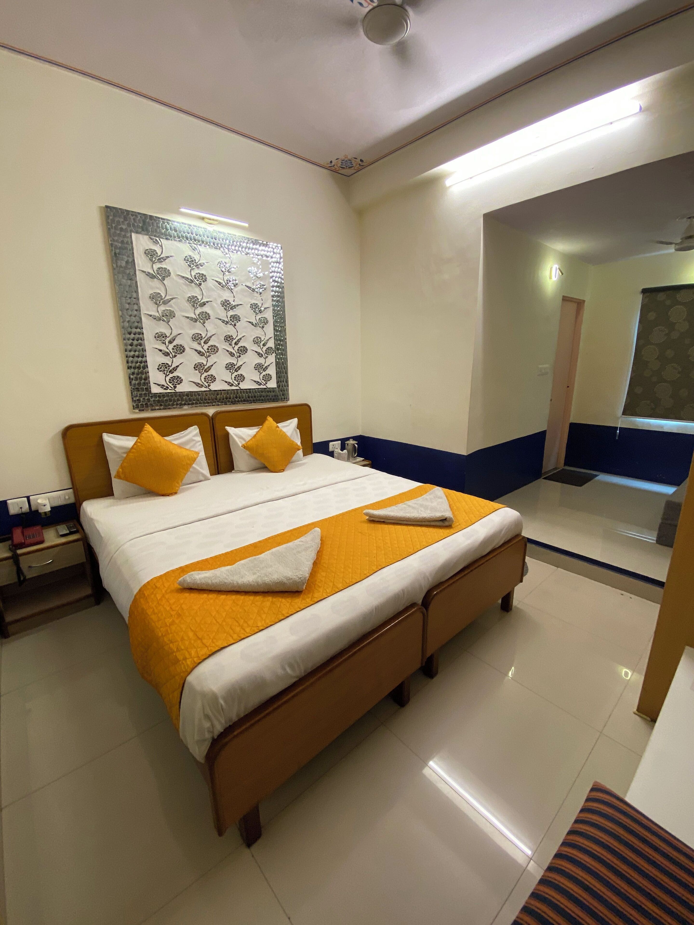A hotel room with a large bed, a nightstand, a mirror, and a decorative wall hanging.