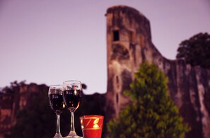 Deux verres à vin et une bougie devant une structure en pierre.