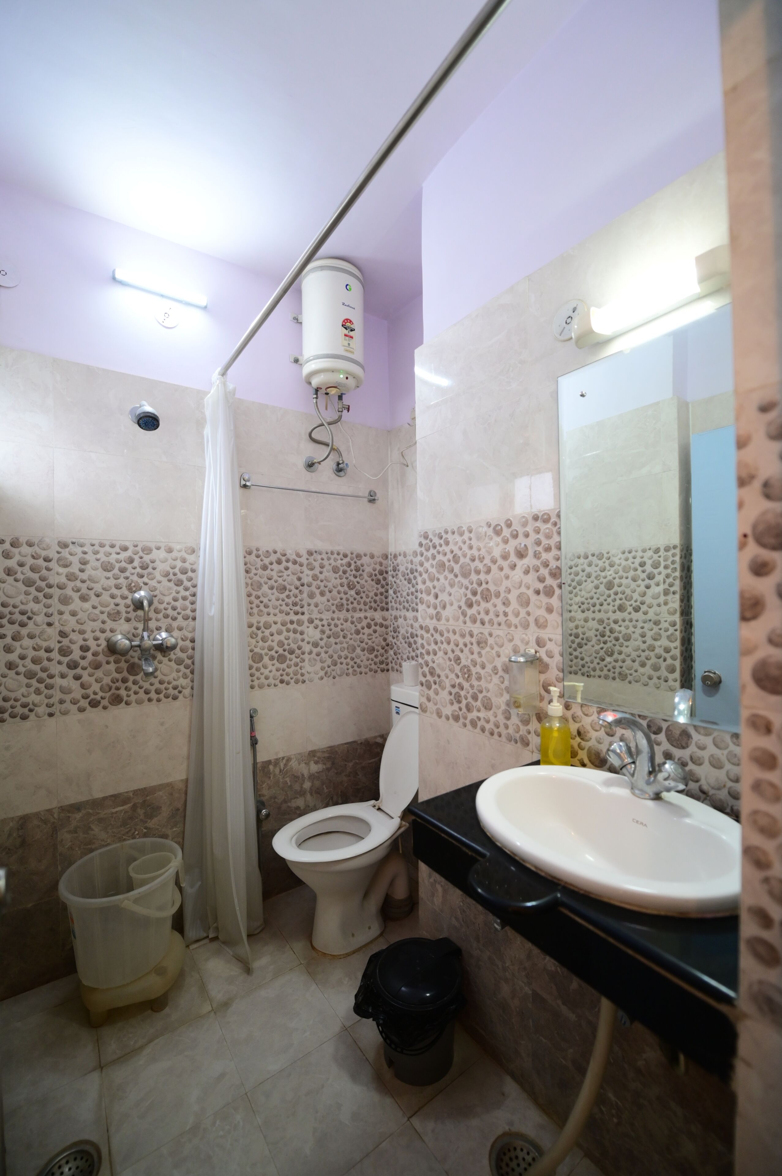 Baño con inodoro, lavamanos, ducha y espejo.