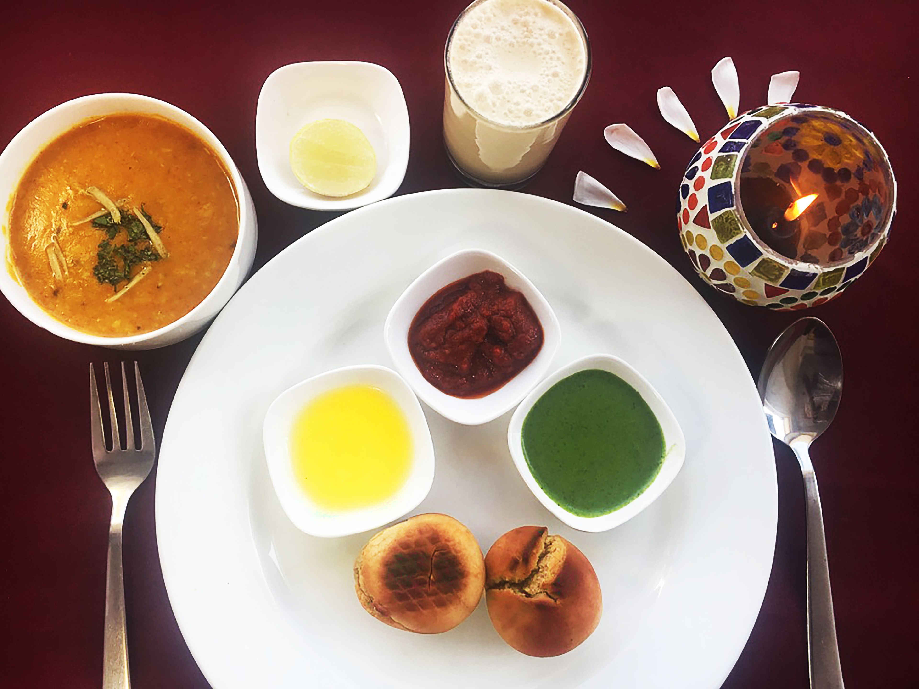 A table with a plate of food including soup, bread, and condiments.