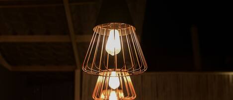 A pendant light fixture with a geometric design hanging from a ceiling with exposed wooden beams.