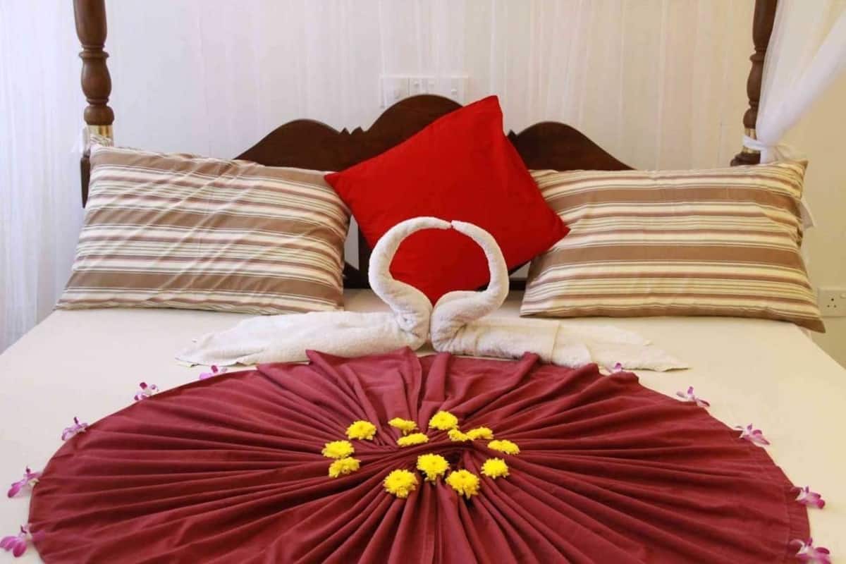 Un lit avec des oreillers à rayures, un oreiller rouge et une disposition de serviettes sur la couverture du lit.