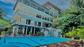 Un hotel con piscina, varios balcones y abundante vegetación.