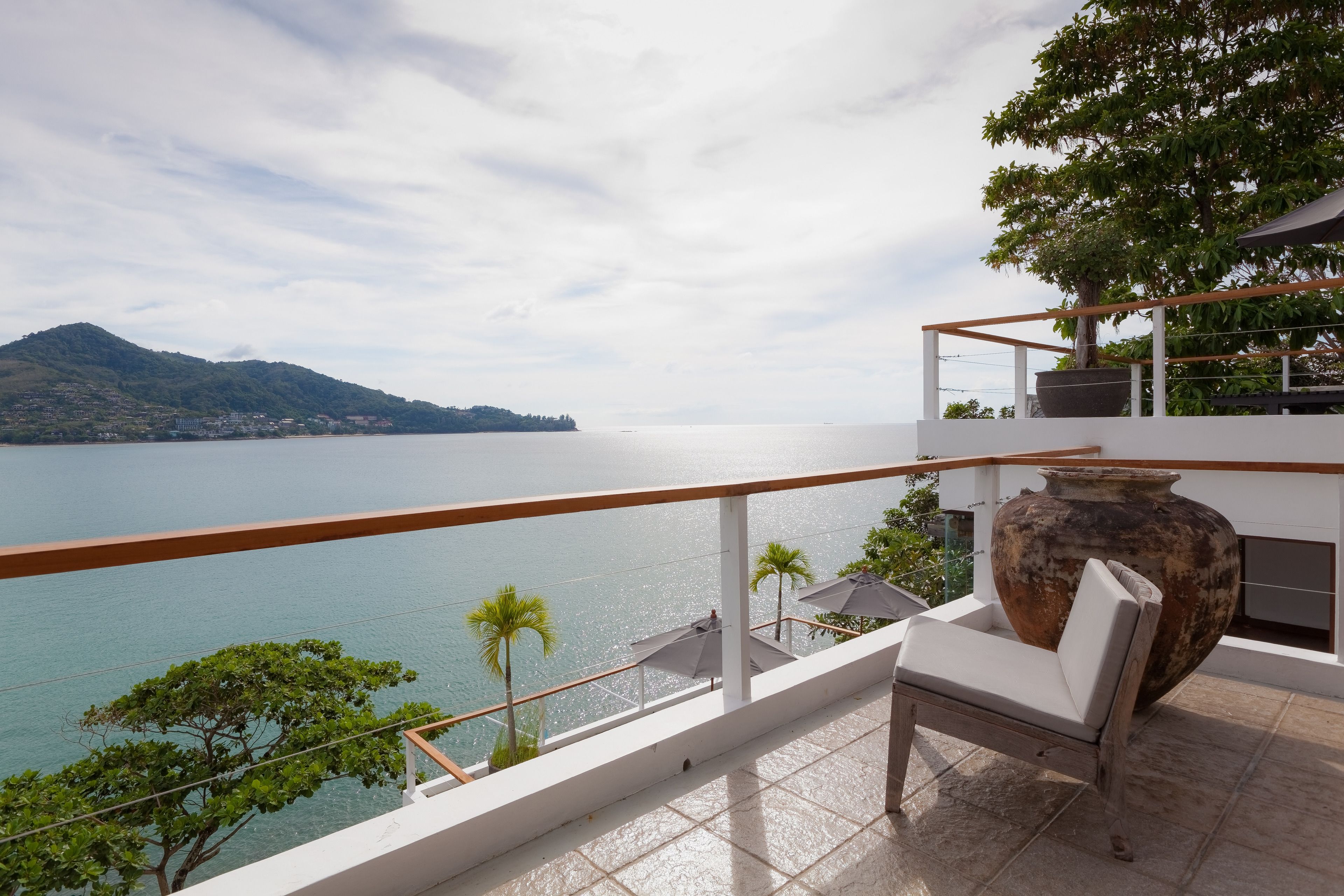 Ein Balkon mit Meerblick, eine große Vase und ein Stuhl.