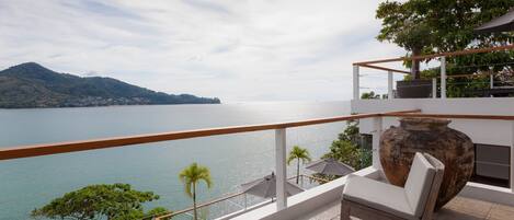 Ein Balkon mit Meerblick, eine große Vase und ein Stuhl.