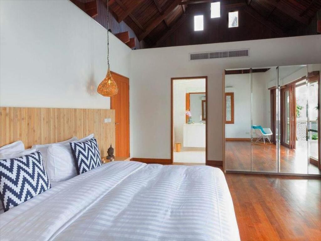 A bedroom with a large bed, wooden headboard, and a hanging light fixture.