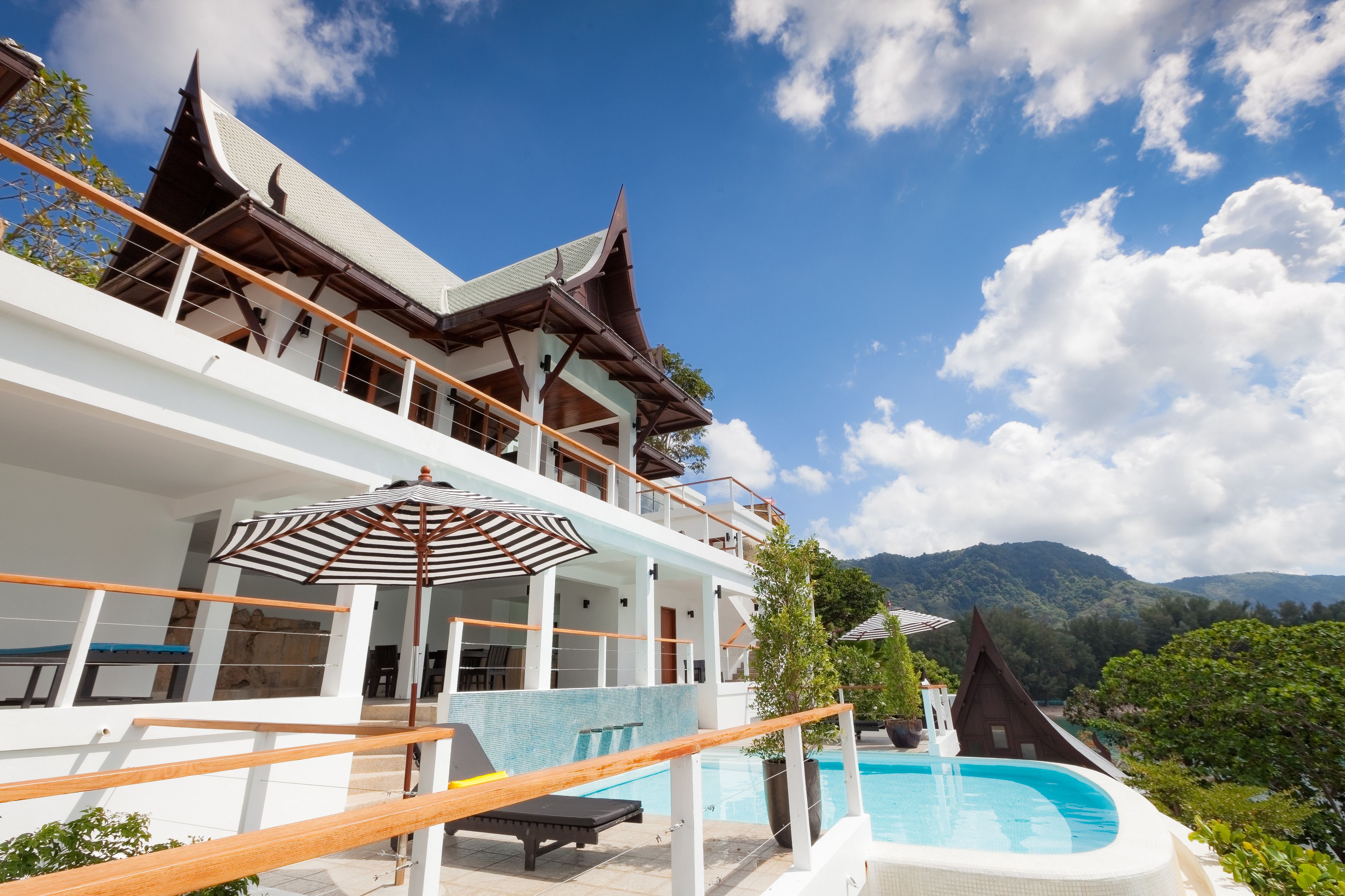 Un resort con piscina, terraza techada y vistas a las montañas.