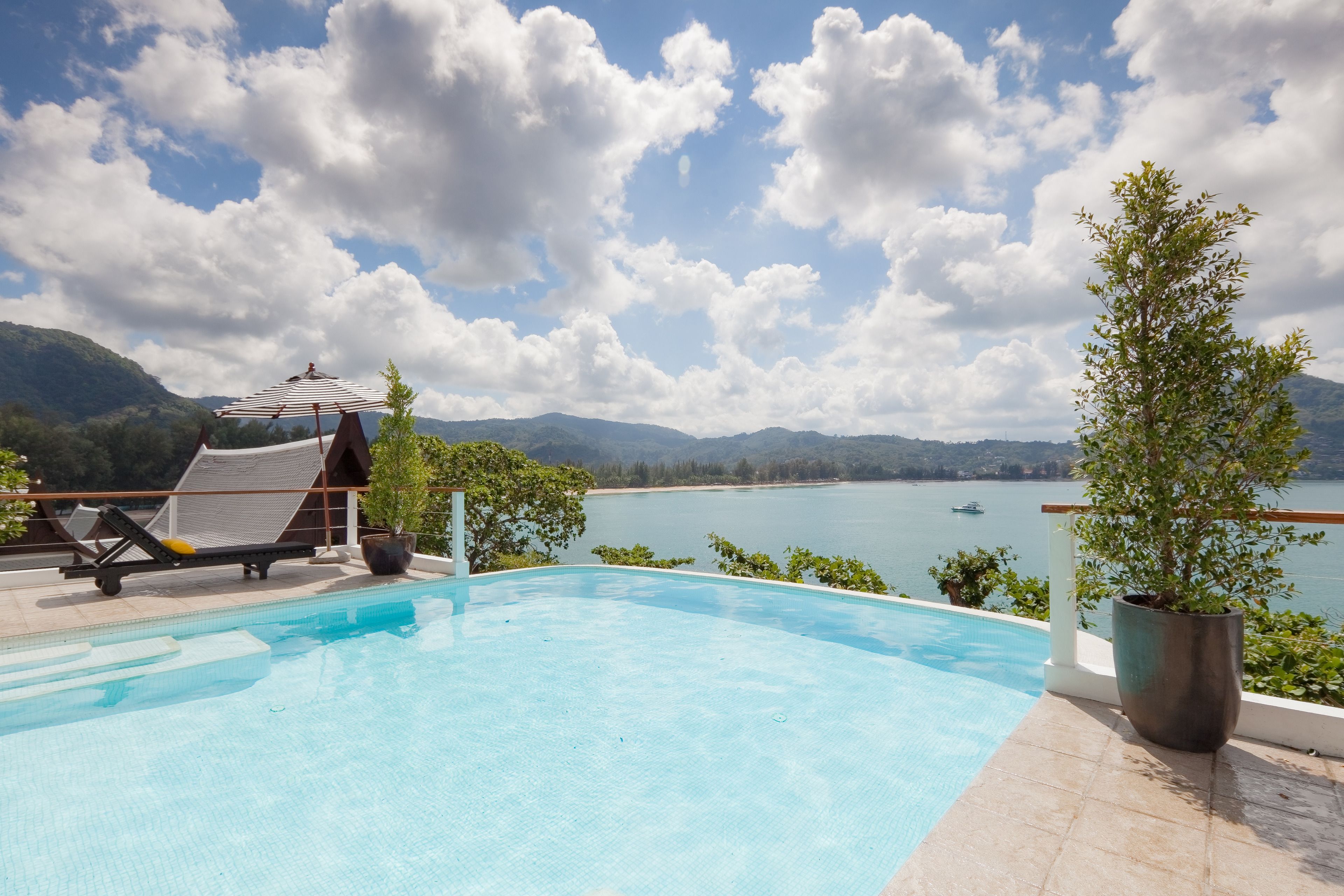 A swimming pool with lounge chairs and a view of a lake and mountains.