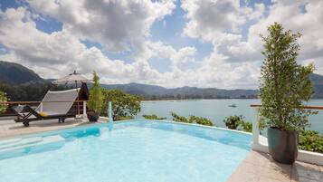 A swimming pool with lounge chairs and a view of a lake and mountains.