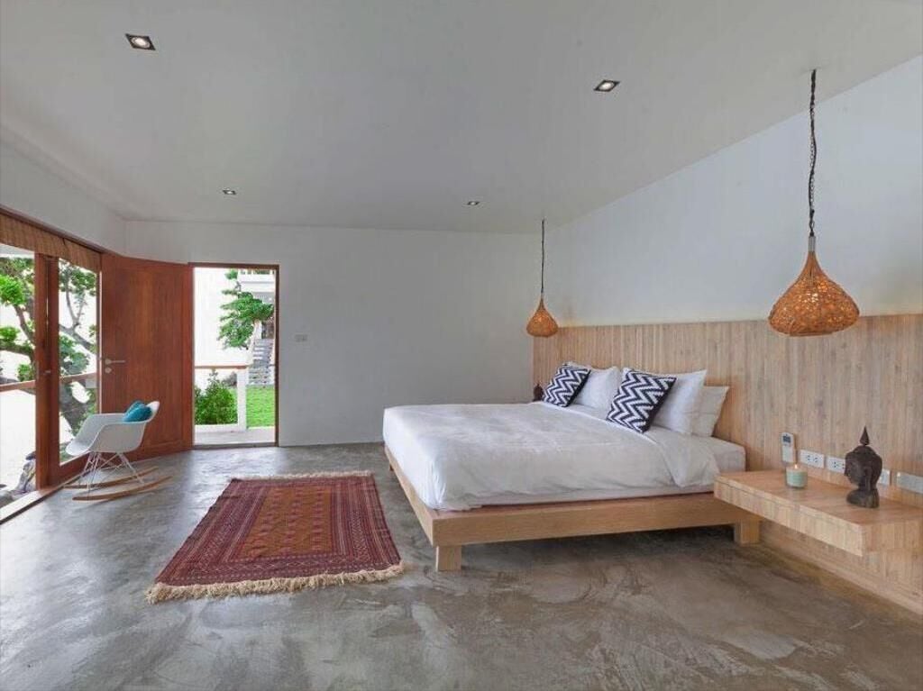 Une chambre moderne avec un lit en bois, un tapis rouge et un luminaire suspendu.