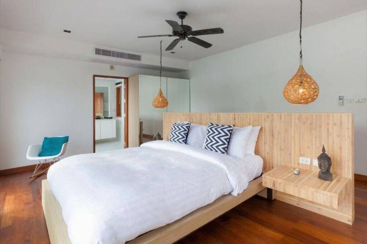 Un dormitorio moderno con una cama de madera, un ventilador de techo y lámparas colgantes.