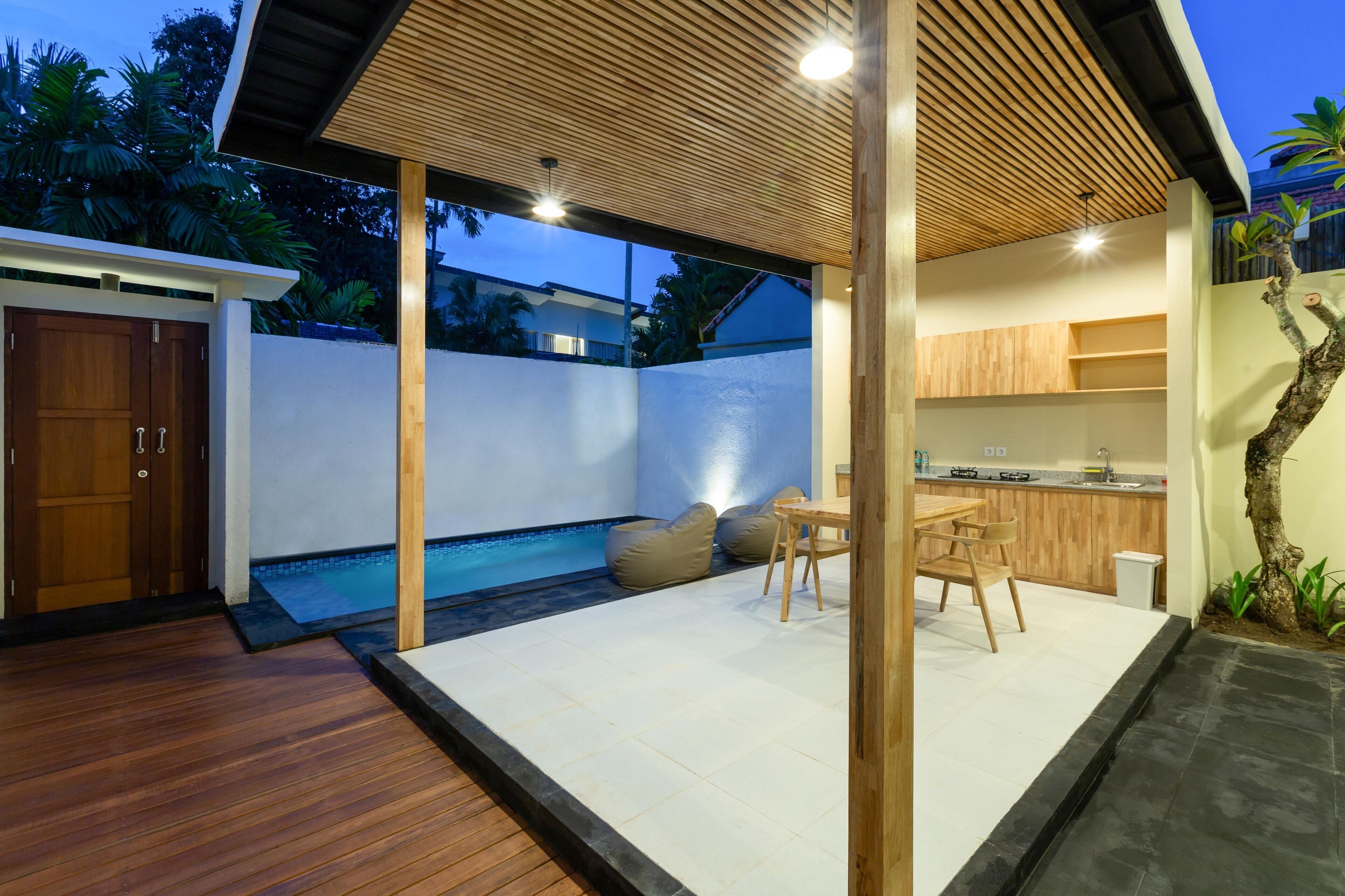 A modern outdoor living area with a wooden deck, a pool, and a dining set.