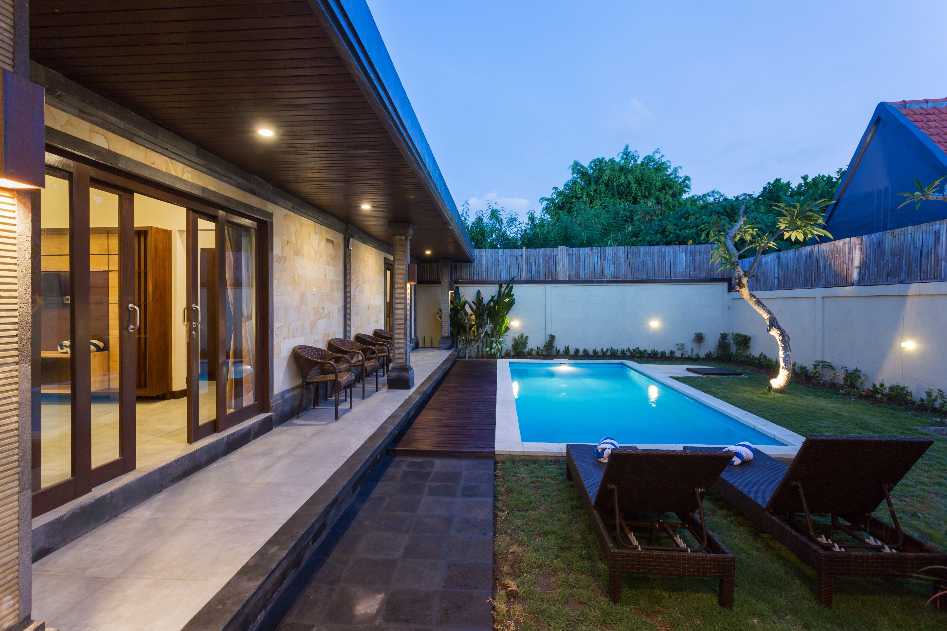 A modern house with a swimming pool, outdoor seating, and a wooden deck.