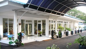A hotel with a covered outdoor area, large windows, and potted plants. - Cengkareng Transit Hotel (Tangerang)