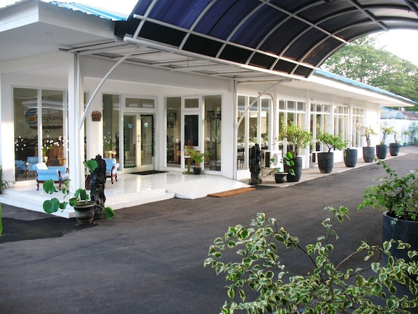 Un hôtel doté d’un espace extérieur abrité, de grandes fenêtres et de plantes en pot.