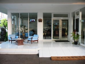 Un vestíbul d'hotel modern amb taulell de recepció, zona de seients i portes de vidre que donen a l'interior.