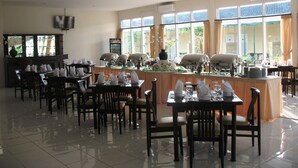 A spacious dining area with multiple tables and chairs, a buffet setup, and large windows allowing natural light. - Cengkareng Transit Hotel (Tangerang)