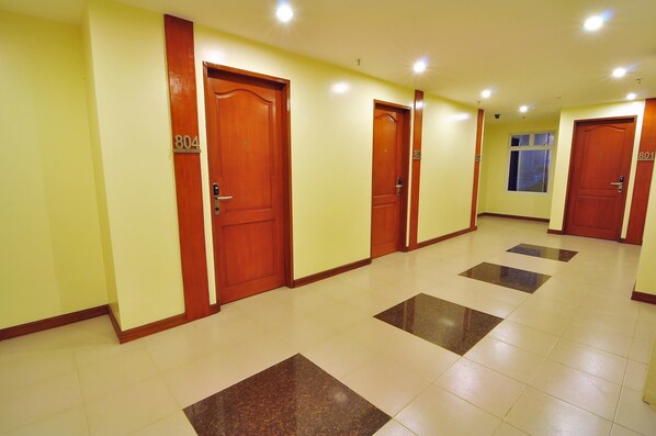 A hotel hallway with wooden doors numbered 804 and 801, tiled floors, and a window with blinds.