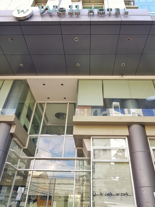 Exterior del Well Hotel, con un diseño moderno, que cuenta con amplios ventanales y un letrero llamativo.