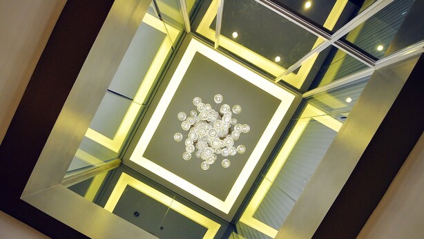 Un plafond moderne orné d’un motif géométrique et surmonté d’un lustre central.