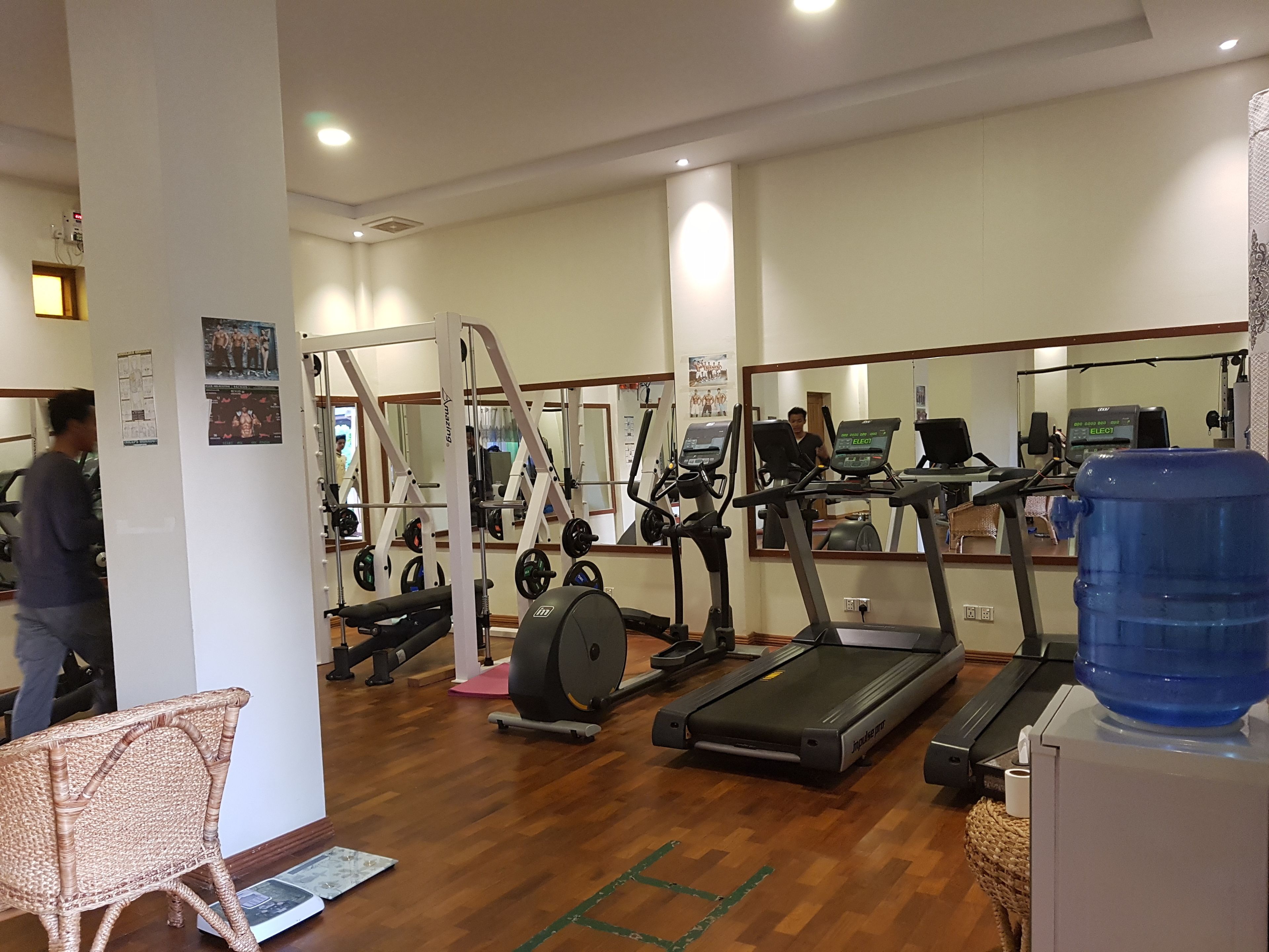 Ein Fitnessstudio mit Laufbändern, Kraftgeräten und einem Wasserspender.