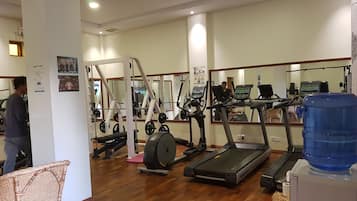 Ein Fitnessstudio mit Laufbändern, Kraftgeräten und einem Wasserspender.