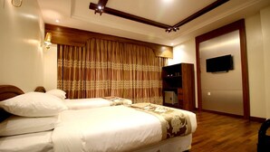 A hotel room with two beds, a wooden headboard, a television, and a wardrobe. - Famous Hotel Bagan (Nyaung-U)