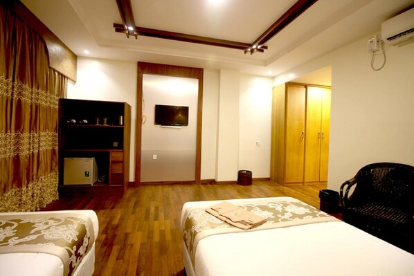 Habitación de hotel con dos camas, televisor, armario y escritorio con computadora.