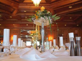 Uma mesa de banquete com toalhas brancas, castiçais de prata e um arranjo floral central.