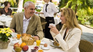 Un desayuno montado con una mesa para dos, que incluye frutas, pastelería y bebidas.