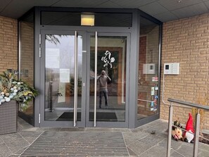 Entrada de hotel con puerta giratoria, puerta de vidrio con un logotipo y pared de ladrillo.
