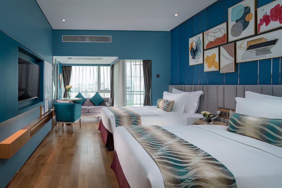 Une chambre d’hôtel avec un grand lit, un canapé, une télévision et une fenêtre avec des rideaux.