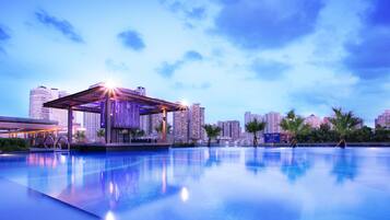 Een buitenzwembad, ligstoelen bij het zwembad