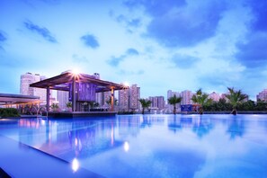 A modern hotel with a rooftop pool, a covered seating area, and a city skyline in the background. - Sentosa Hotel Apartment Taoyuan Branch (Shenzhen)