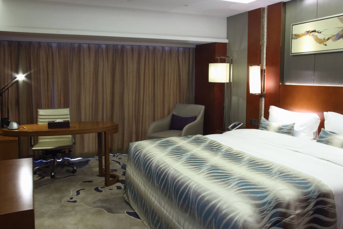 Une chambre d’hôtel avec un grand lit, un bureau, une chaise et une lampe.