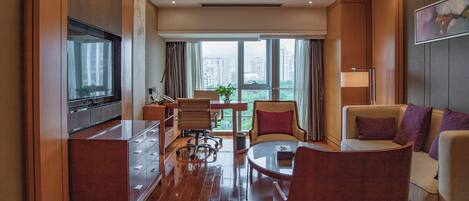 A modern hotel room with a kitchen, dining area, and seating space.