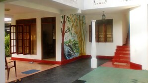 Un interior espacioso con una escalera, un mural y un balcón.