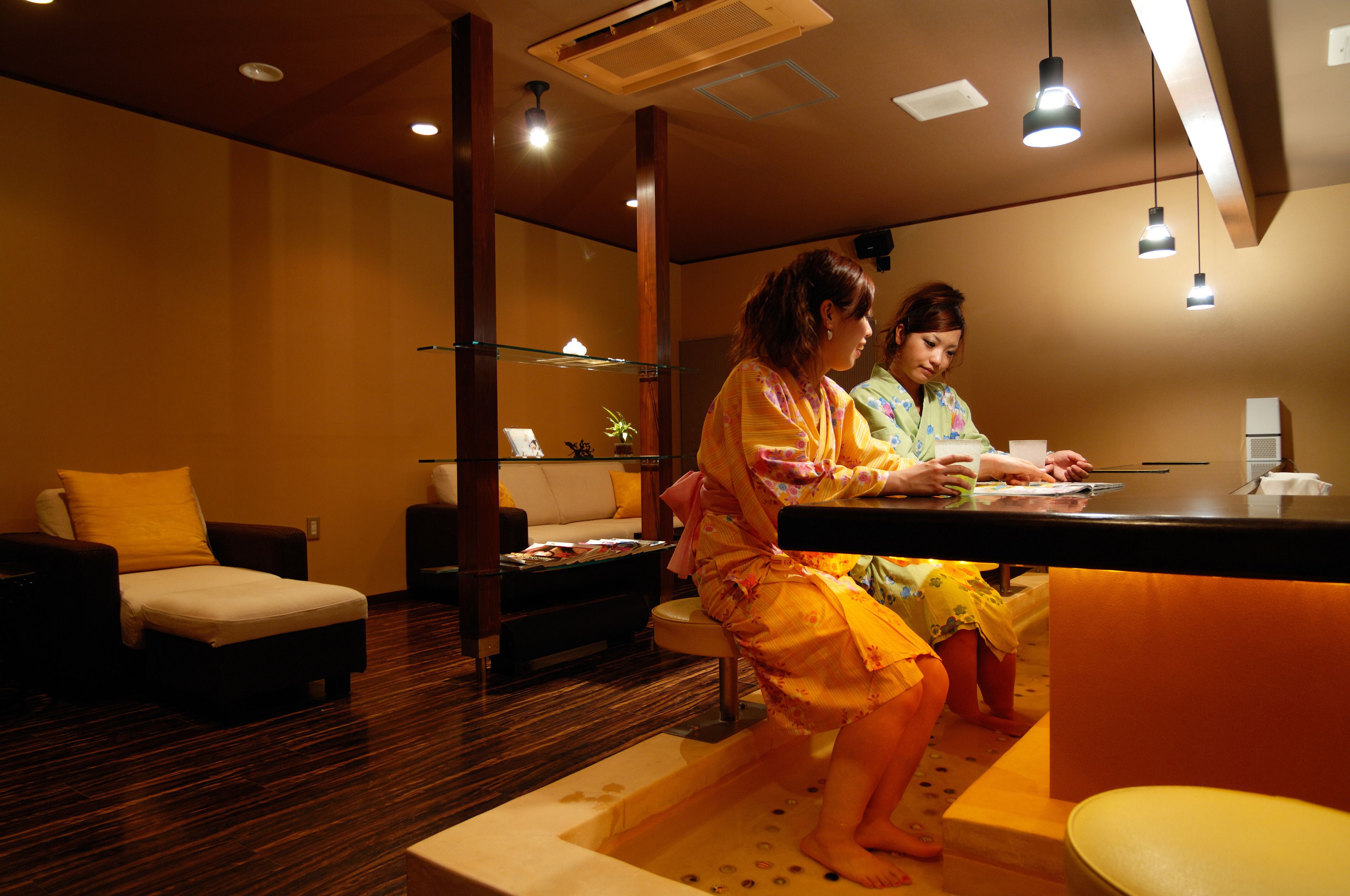 A spa room with wooden flooring, a massage table, and a reception desk.