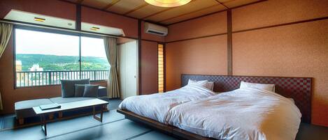A hotel room with a large bed, a sofa, a view of the city, and a wooden ceiling.