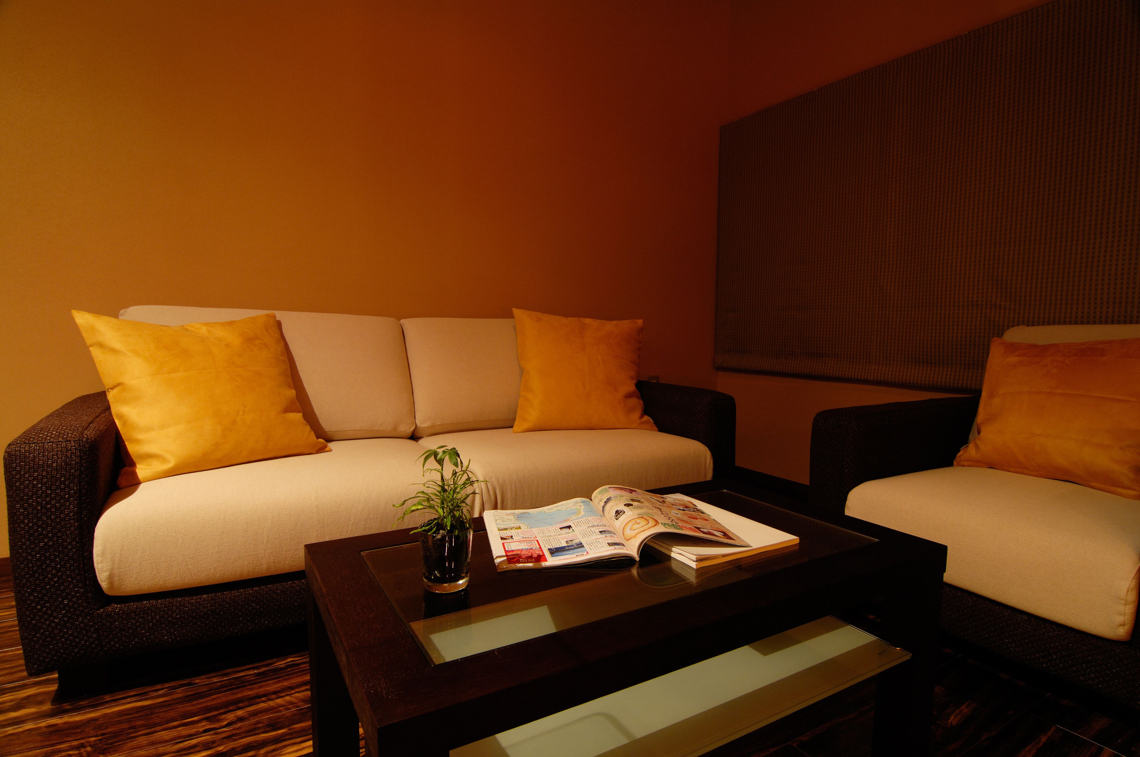 A modern living room with a sofa, two armchairs, a coffee table, and a magazine.