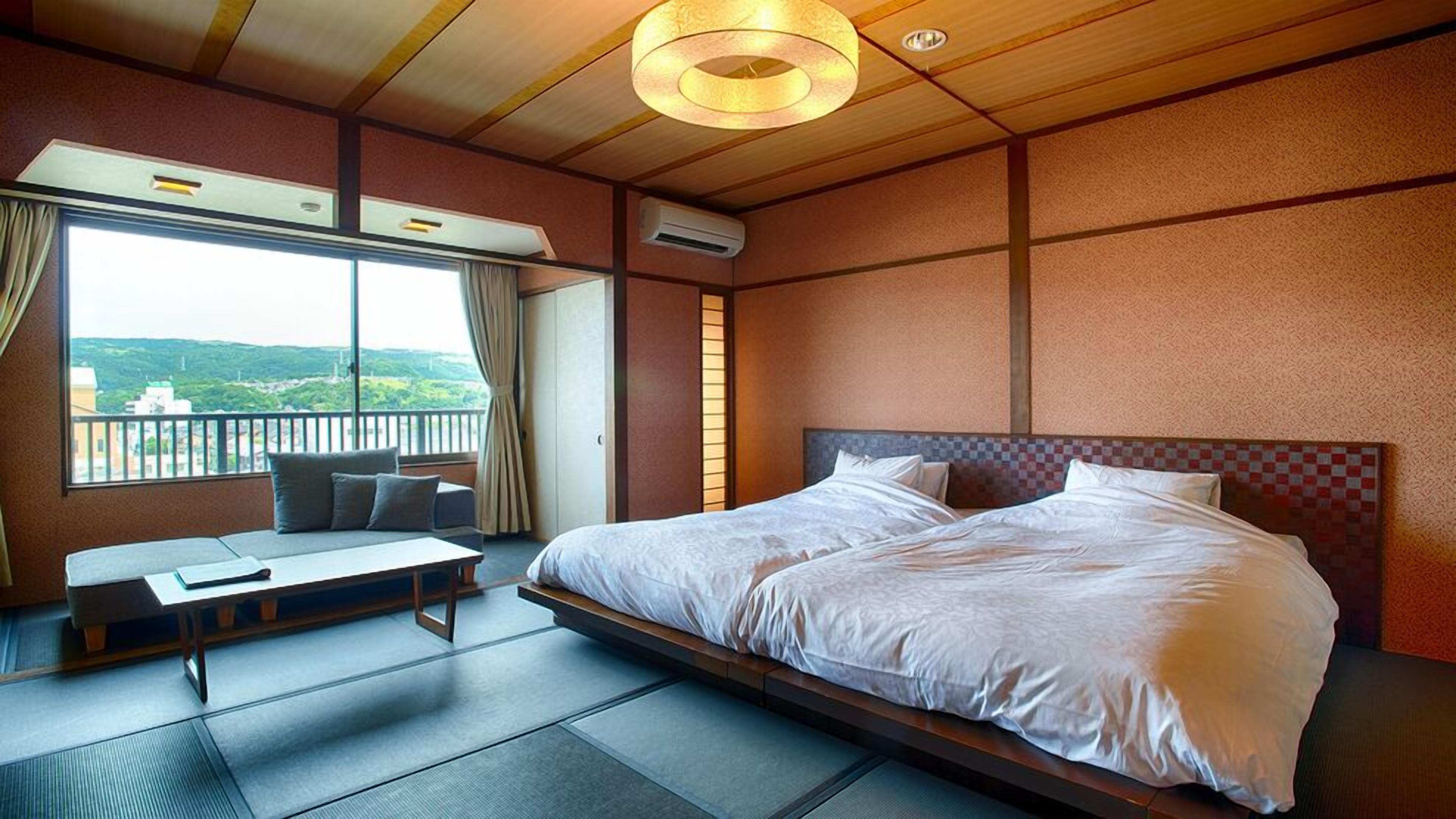A hotel room with a large bed, a sofa, a table, and a view of the outdoors.