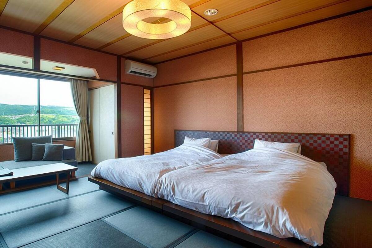Une chambre d’hôtel avec un grand lit, un canapé, une table et une vue sur l’extérieur.