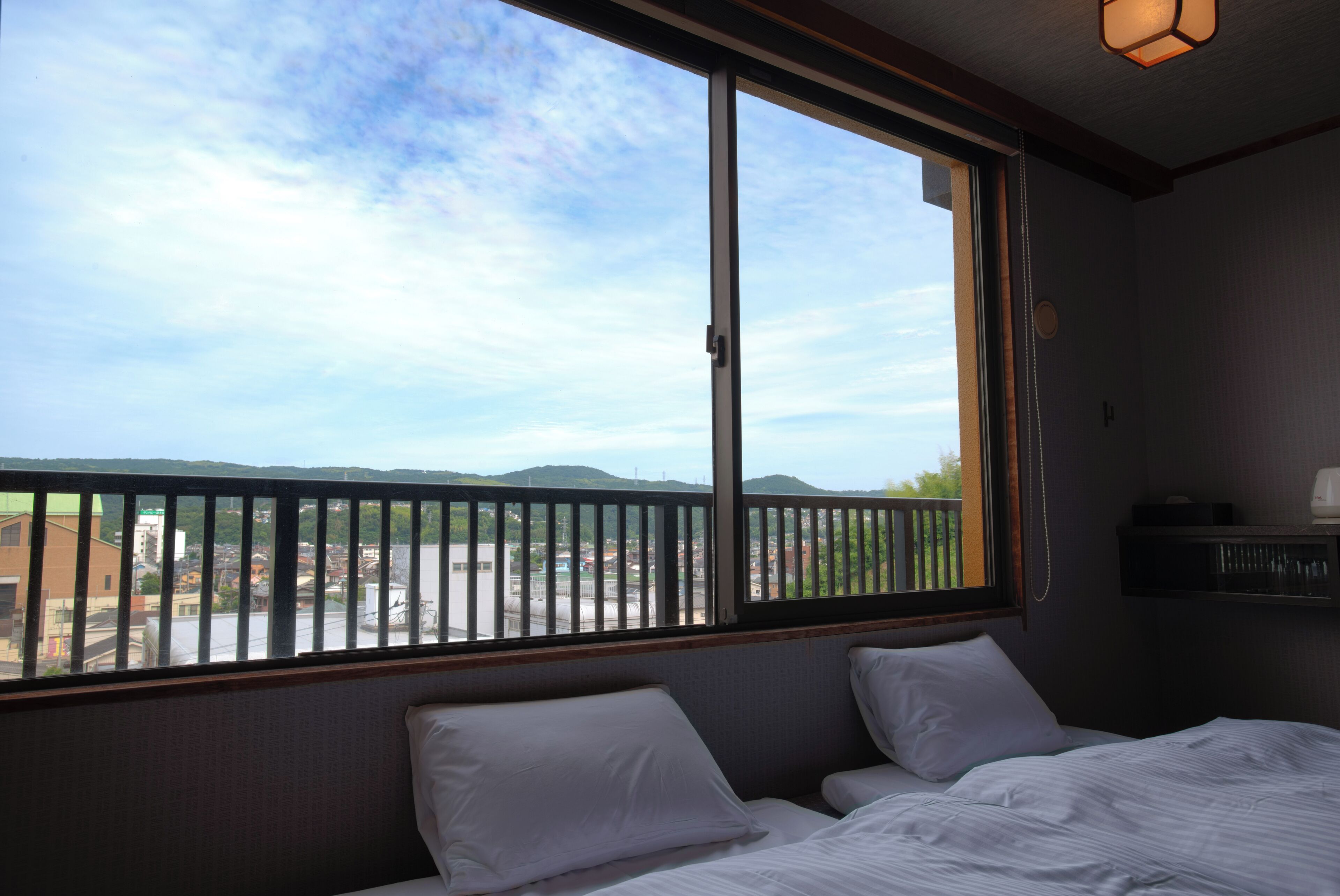 Una habitación de hotel con un ventanal grande, una cama y una mesita de noche.